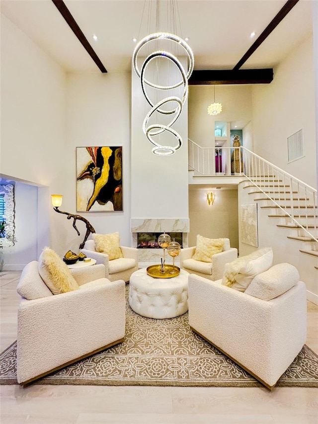 living room with beamed ceiling, a chandelier, a high ceiling, and wood-type flooring