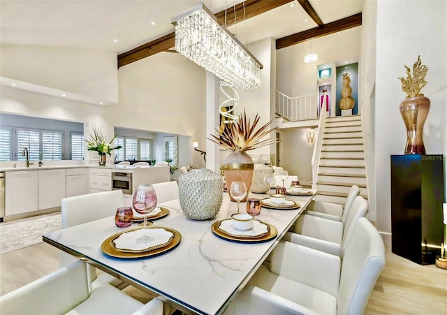 dining room featuring high vaulted ceiling, sink, beam ceiling, a notable chandelier, and light hardwood / wood-style floors