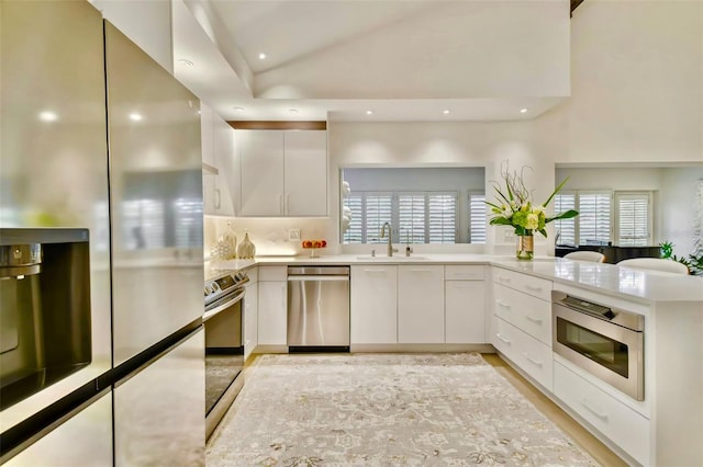 kitchen with white cabinets, sink, kitchen peninsula, and stainless steel appliances