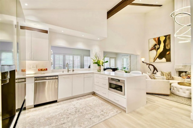 kitchen with high vaulted ceiling, beamed ceiling, white cabinetry, kitchen peninsula, and stainless steel appliances