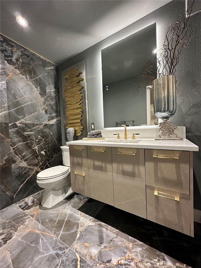 bathroom with vanity, toilet, and tile walls