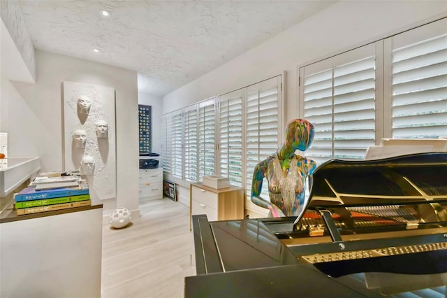 recreation room with light hardwood / wood-style floors and a textured ceiling