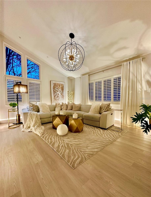 living room with hardwood / wood-style floors, an inviting chandelier, and lofted ceiling