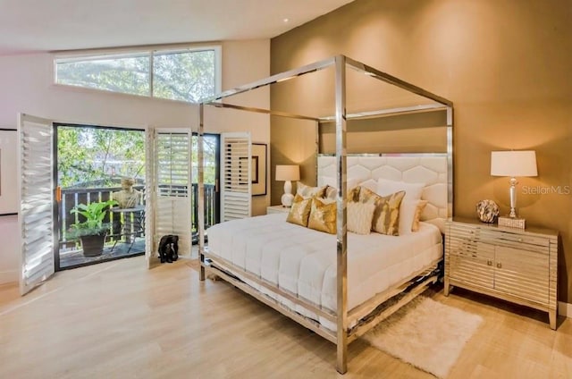 bedroom with access to exterior, high vaulted ceiling, and wood-type flooring