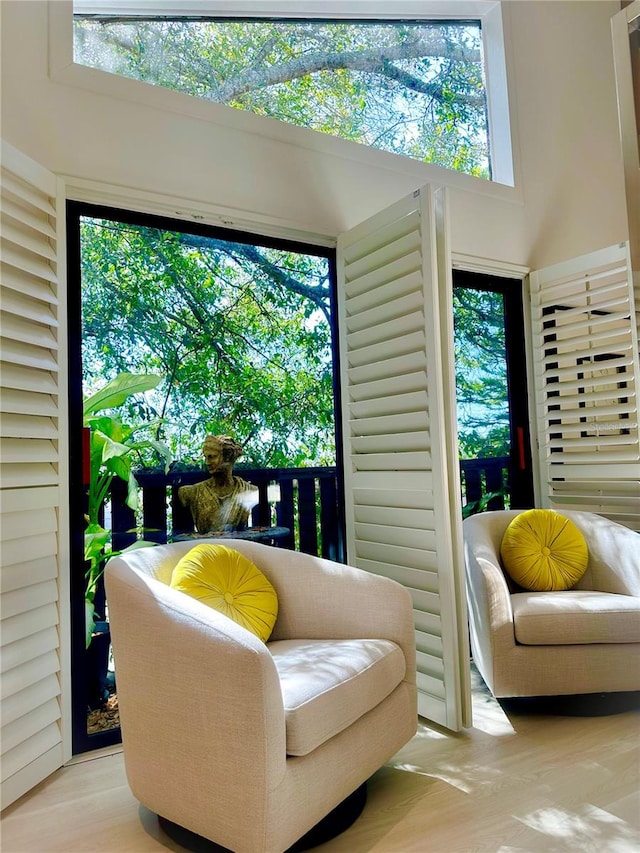 living area featuring a towering ceiling, light hardwood / wood-style flooring, and plenty of natural light