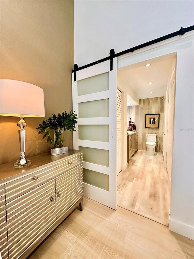 corridor with hardwood / wood-style flooring, a barn door, and wood walls