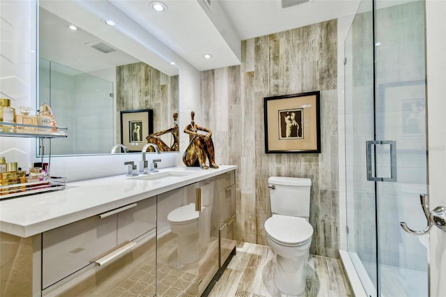 bathroom featuring wood-type flooring, an enclosed shower, toilet, vanity, and tile walls