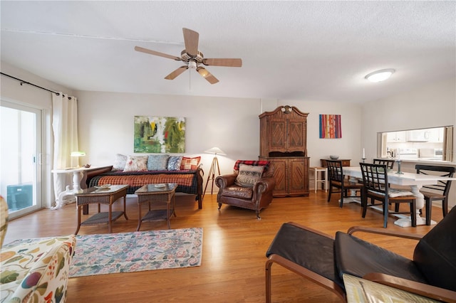 living room with ceiling fan, light hardwood / wood-style floors, and a textured ceiling