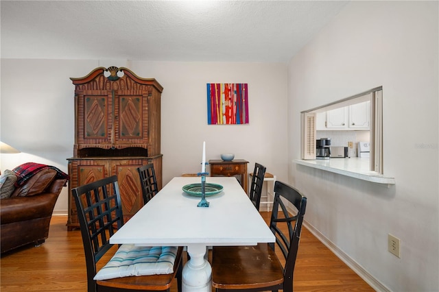 dining space featuring light wood-type flooring and a textured ceiling