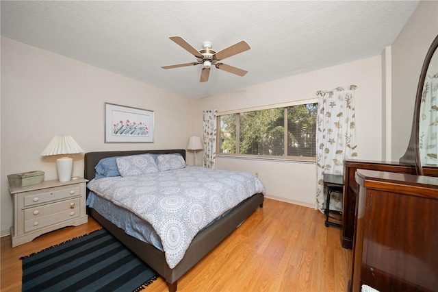 bedroom featuring ceiling fan, light hardwood / wood-style floors, and a textured ceiling