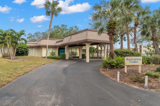 11485 Oakhurst Rd Unit 322, Largo, FL 33774 - view of front facade featuring a front lawn, stucco siding, asphalt driveway, a carport, and mansard roof