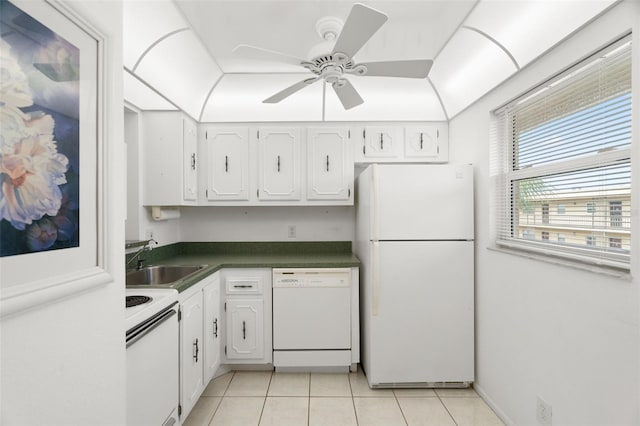 kitchen with dark countertops, light tile patterned flooring, a sink, white cabinets, and white appliances