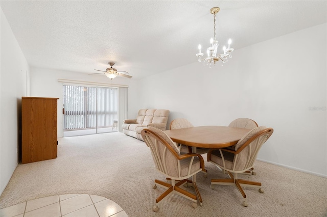 carpeted dining area featuring a textured ceiling and ceiling fan with notable chandelier