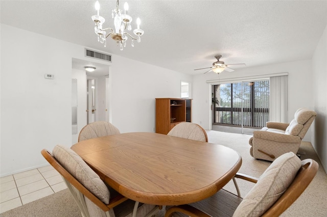 tiled dining room with ceiling fan with notable chandelier and a textured ceiling