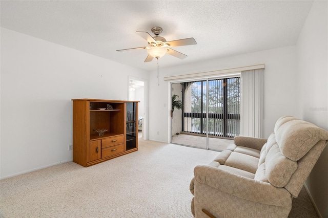 living room featuring ceiling fan, light colored carpet, and a textured ceiling