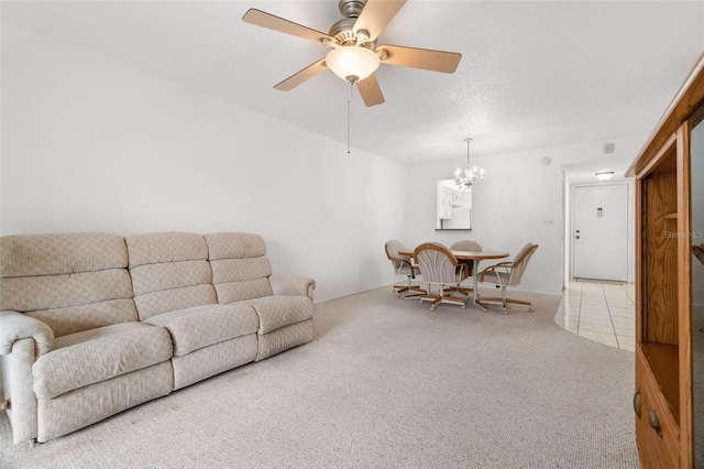 carpeted living room with ceiling fan with notable chandelier