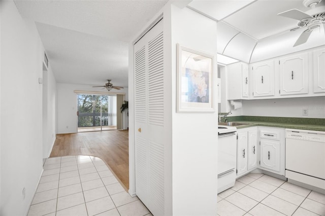 kitchen featuring white appliances, light tile patterned floors, white cabinetry, and a sink