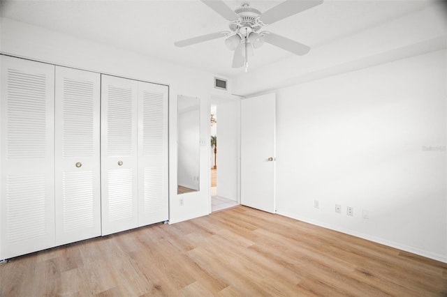 unfurnished bedroom featuring a ceiling fan, a closet, visible vents, and wood finished floors