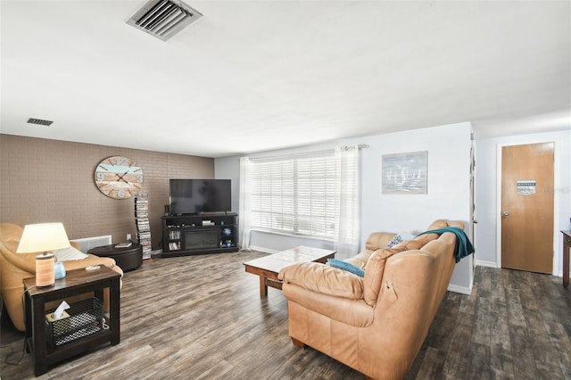 living room featuring brick wall and dark hardwood / wood-style floors