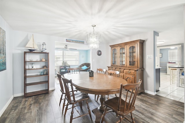 dining space featuring ceiling fan with notable chandelier and dark wood-type flooring