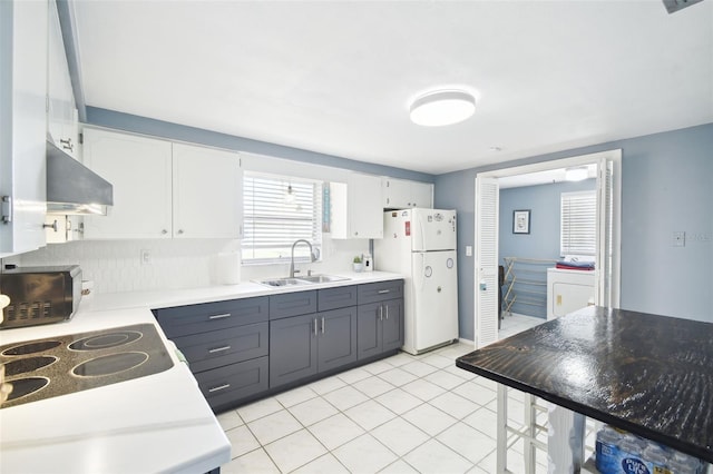 kitchen with separate washer and dryer, white cabinetry, sink, and white fridge