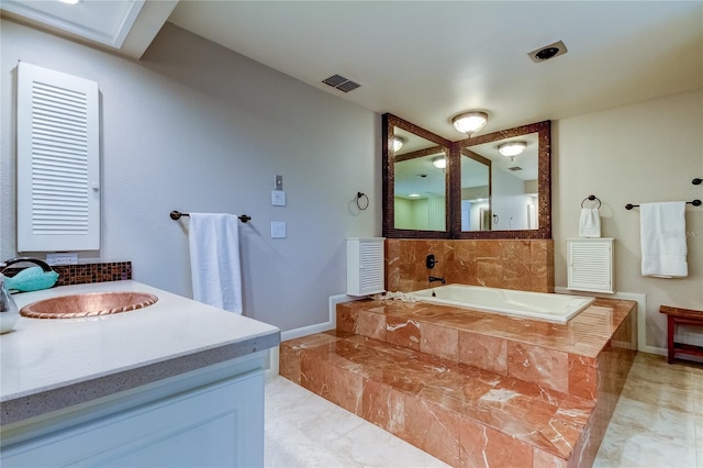 bathroom featuring tiled bath, vanity, and tile patterned floors