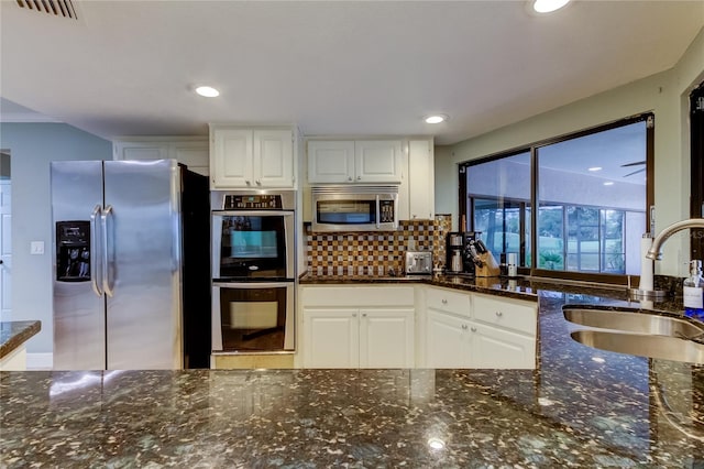 kitchen featuring dark stone counters, decorative backsplash, sink, white cabinetry, and appliances with stainless steel finishes