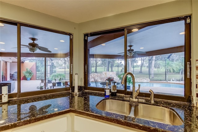 kitchen with dark stone counters, sink, ceiling fan, and white cabinets