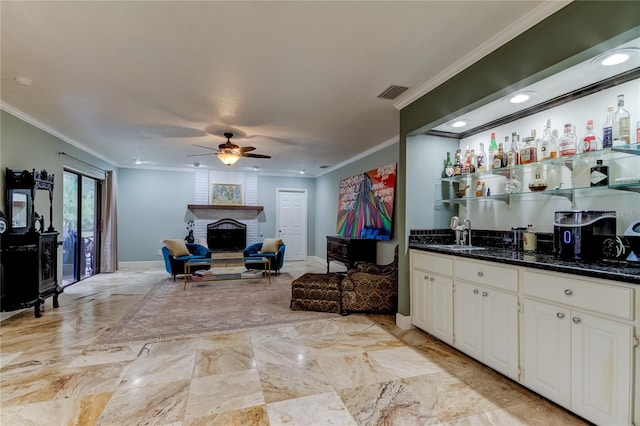 interior space featuring ornamental molding, white cabinetry, sink, a brick fireplace, and ceiling fan