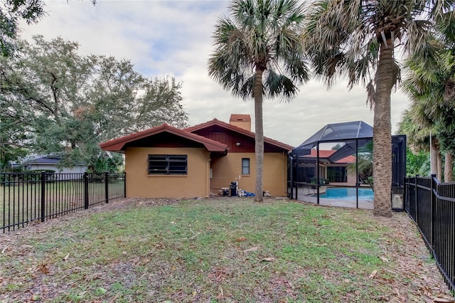 back of property featuring a yard, a fenced in pool, and glass enclosure