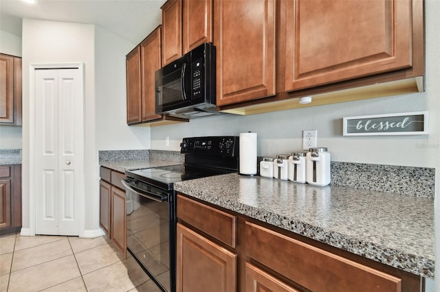 kitchen with black appliances, stone counters, and light tile patterned floors