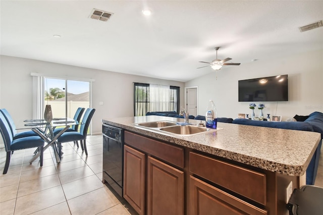 kitchen featuring lofted ceiling, black dishwasher, sink, light tile patterned floors, and an island with sink