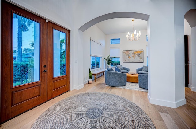 entrance foyer featuring french doors, a chandelier, and light wood-type flooring