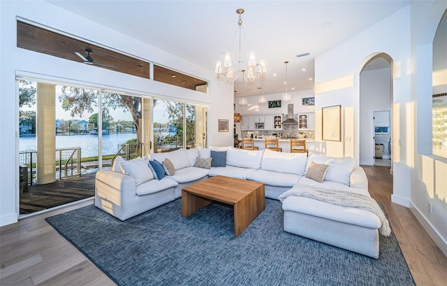 living room with a water view, a towering ceiling, wood-type flooring, and a notable chandelier