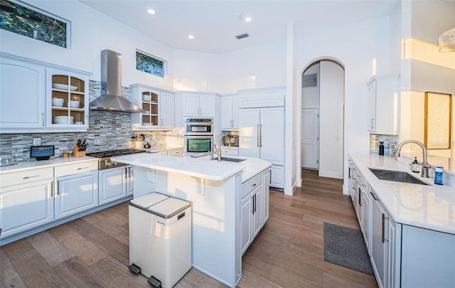 kitchen with white cabinets, sink, a center island with sink, and exhaust hood