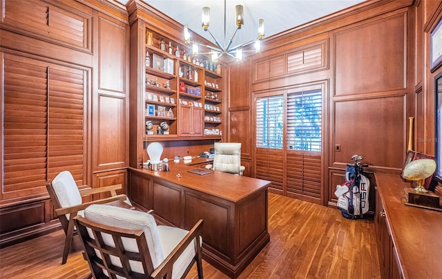 home office featuring hardwood / wood-style flooring, a chandelier, and wood walls