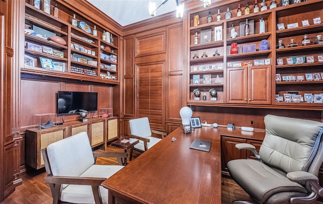 home office with dark wood-type flooring, wooden walls, and built in features