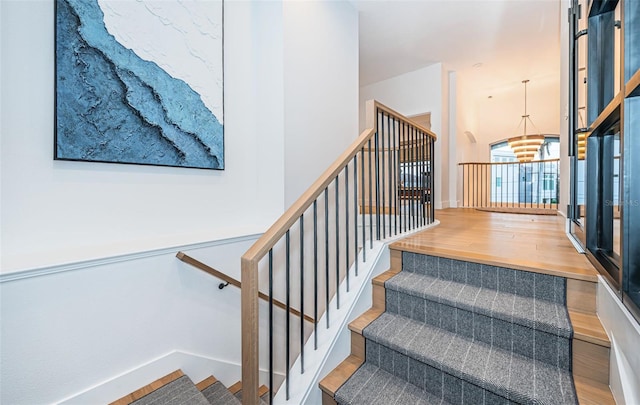 stairway featuring hardwood / wood-style flooring and an inviting chandelier