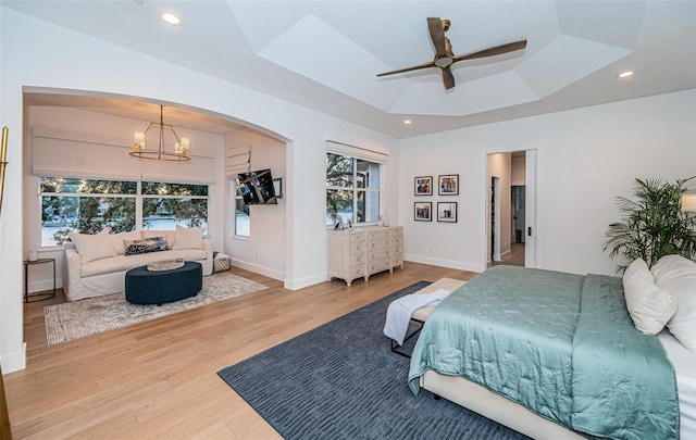 bedroom featuring hardwood / wood-style flooring, a tray ceiling, and a notable chandelier