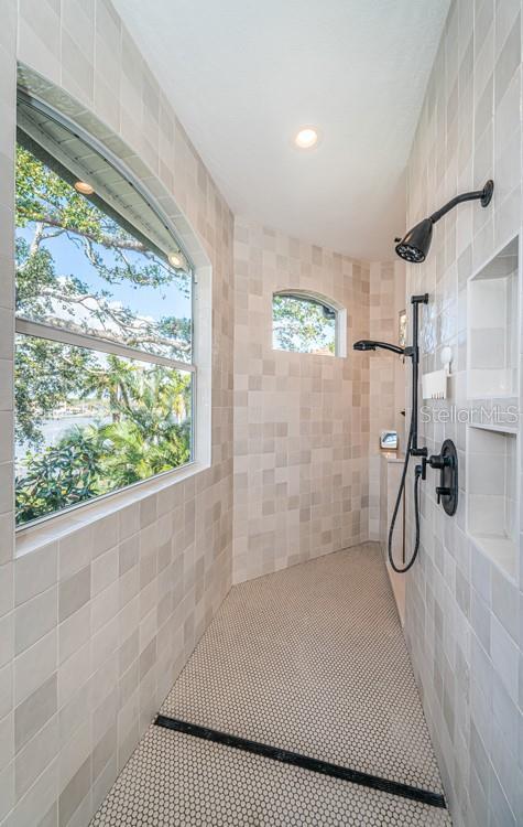 bathroom with tiled shower and tile patterned flooring