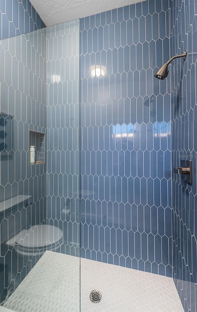 bathroom with tiled shower and a textured ceiling