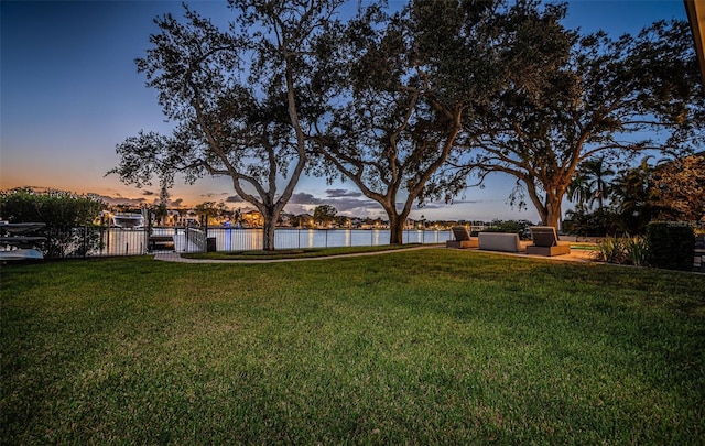 yard at dusk featuring a water view