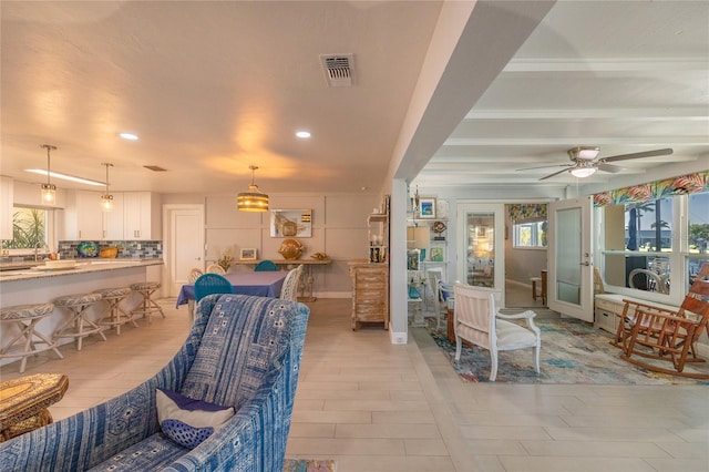 tiled living room featuring ceiling fan and sink