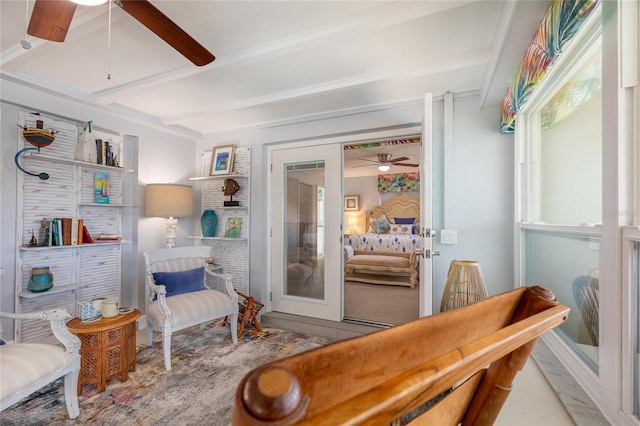 living area featuring ceiling fan and beamed ceiling