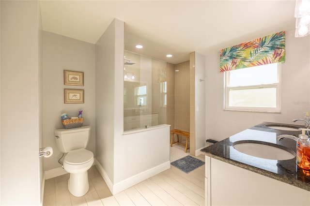 bathroom with vanity, toilet, and tiled shower