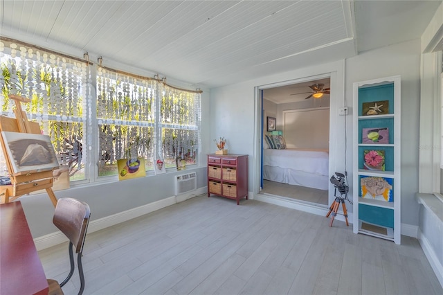 sunroom featuring a wall unit AC and ceiling fan