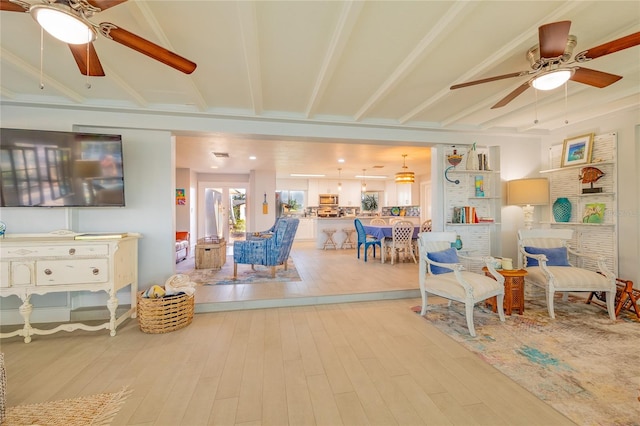 interior space featuring beamed ceiling, ceiling fan, and light wood-type flooring