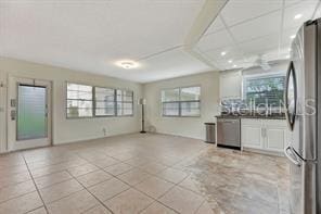 interior space featuring stainless steel appliances, light tile patterned flooring, a healthy amount of sunlight, and white cabinetry