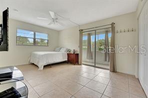 bedroom featuring light tile patterned flooring, ceiling fan, multiple windows, and access to exterior