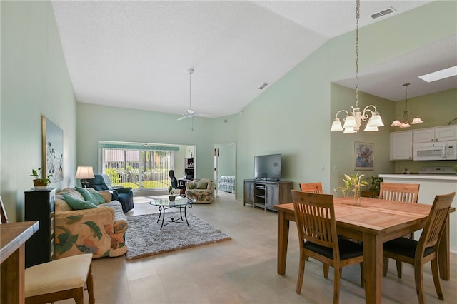 dining room featuring a skylight, high vaulted ceiling, and ceiling fan with notable chandelier